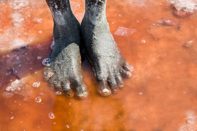 The feet of a salt miner &lt;p&gt;standing in the salt water of Lake Natron