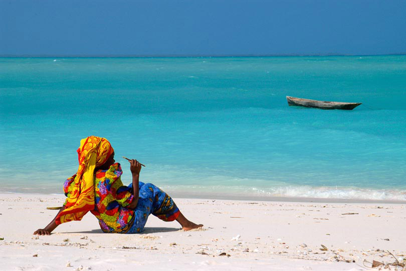 Woman in traditional dress rests &lt;p&gt;on the beach of Zanzibar
